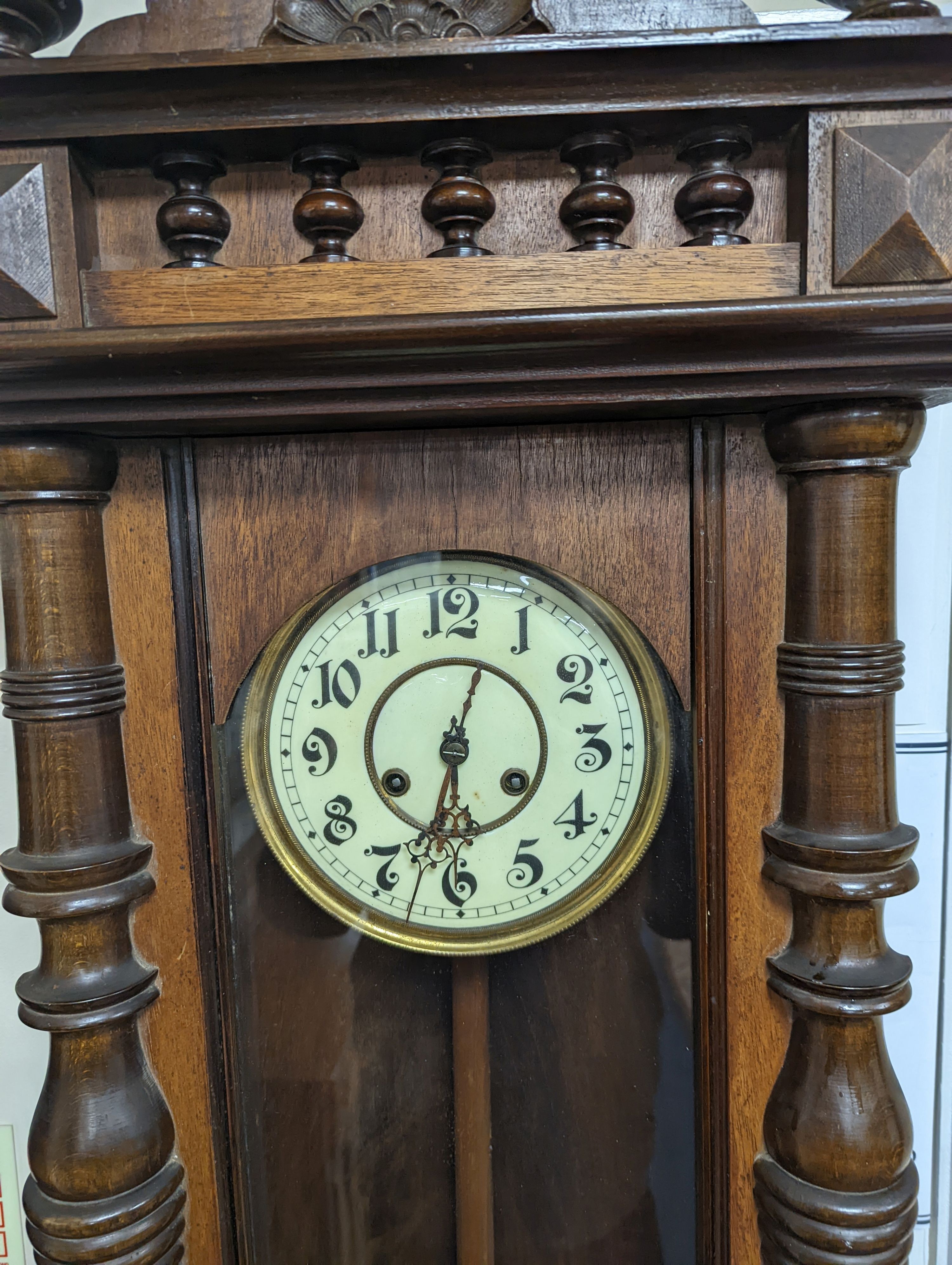 A late 19th century Austrian walnut wall clock, with key and pendulum, height 118cm